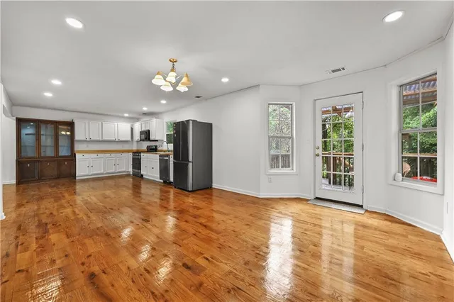 a view of an empty room with kitchen and window