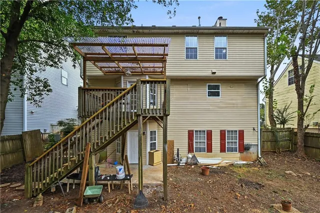 a view of a white house with a large tree and wooden fence