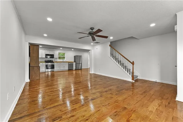 a view of an empty room with kitchen and a window