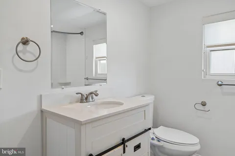 a bathroom with a toilet sink vanity and mirror