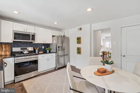 a kitchen with stainless steel appliances granite countertop a sink dishwasher a refrigerator and a stove with wooden floor