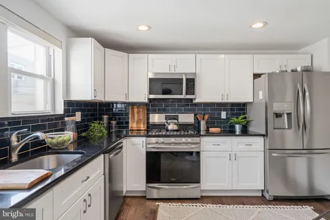 a kitchen with stainless steel appliances granite countertop a stove a sink a refrigerator a microwave and cabinets