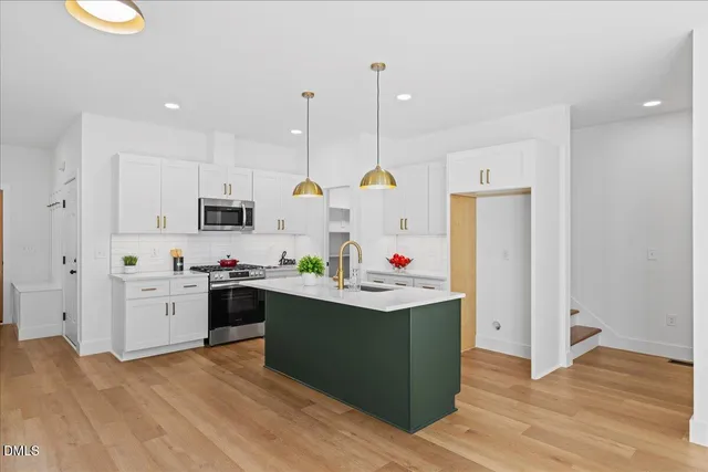 a kitchen with stainless steel appliances kitchen island granite countertop a refrigerator a stove top oven and a wooden floors