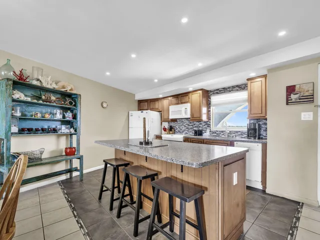 a kitchen with stainless steel appliances granite countertop a table chairs sink and cabinets