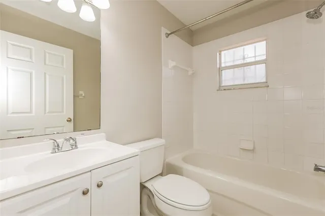 a bathroom with a bathtub shower sink vanity mirror and toilet