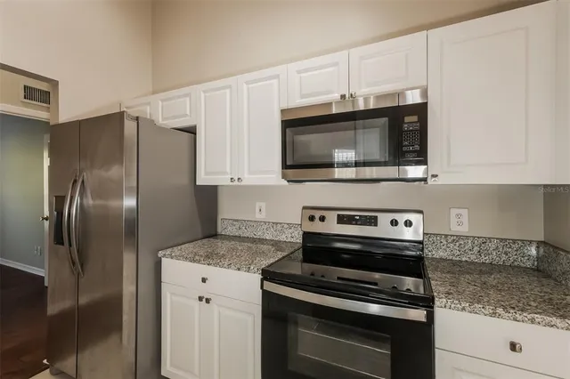a kitchen with granite countertop a stove microwave and refrigerator