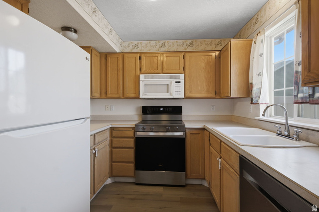 794 East 950 S Street Provo, UT 84606 - Photo 7 of 28 U-shaped kitchen layout featuring wood cabinetry, a stainless steel range, a built-in microwave, and a double basin sink beneath a window