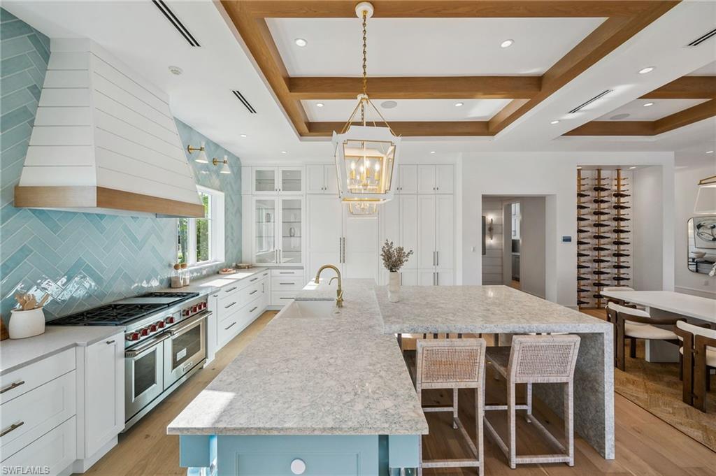 187 10th Avenue South Naples, FL 34102 - Photo 10 of 48 a kitchen with stainless steel appliances granite countertop a stove a refrigerator a kitchen island with white cabinets and wooden floor