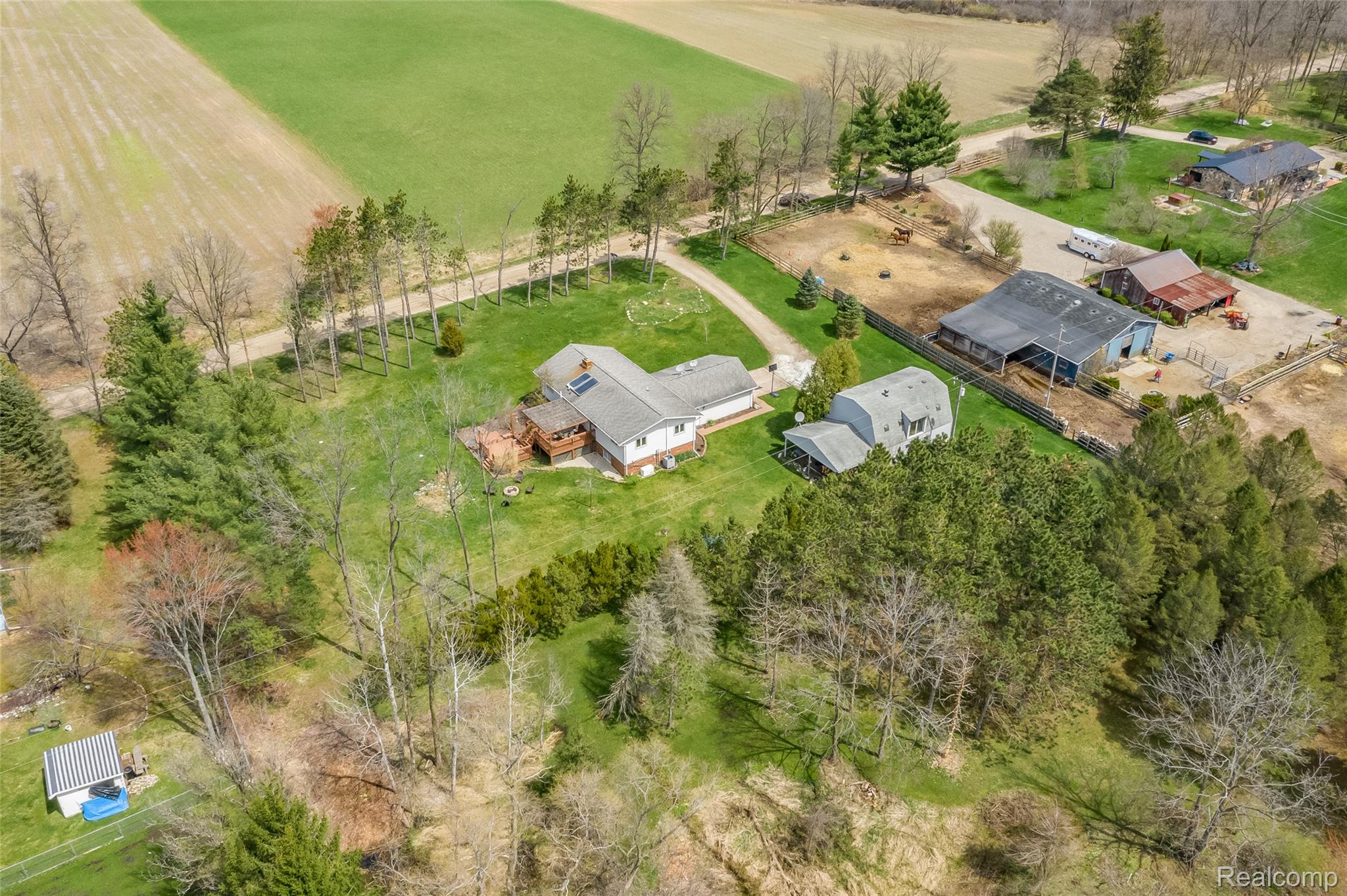 15395 Osius Road Chelsea, MI 48118 - Photo 53 of 55 Expansive property featuring a primary residence with a deck, a detached outbuilding, a large barn, and an additional smaller outbuilding