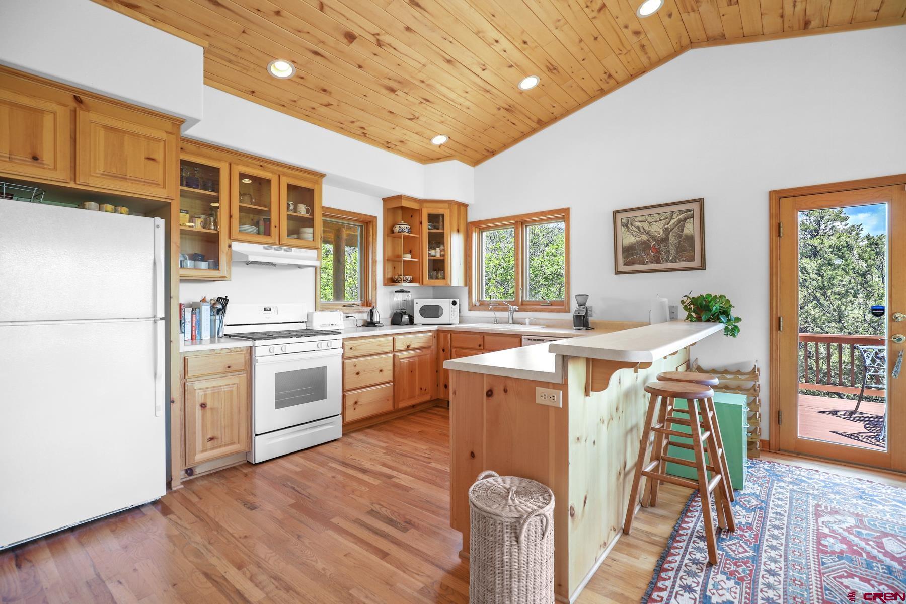 756 Horse Gulch Loop Durango, CO 81301 - Photo 28 of 35 a open kitchen with a refrigerator a stove top oven a sink dishwasher and white cabinets with wooden floor