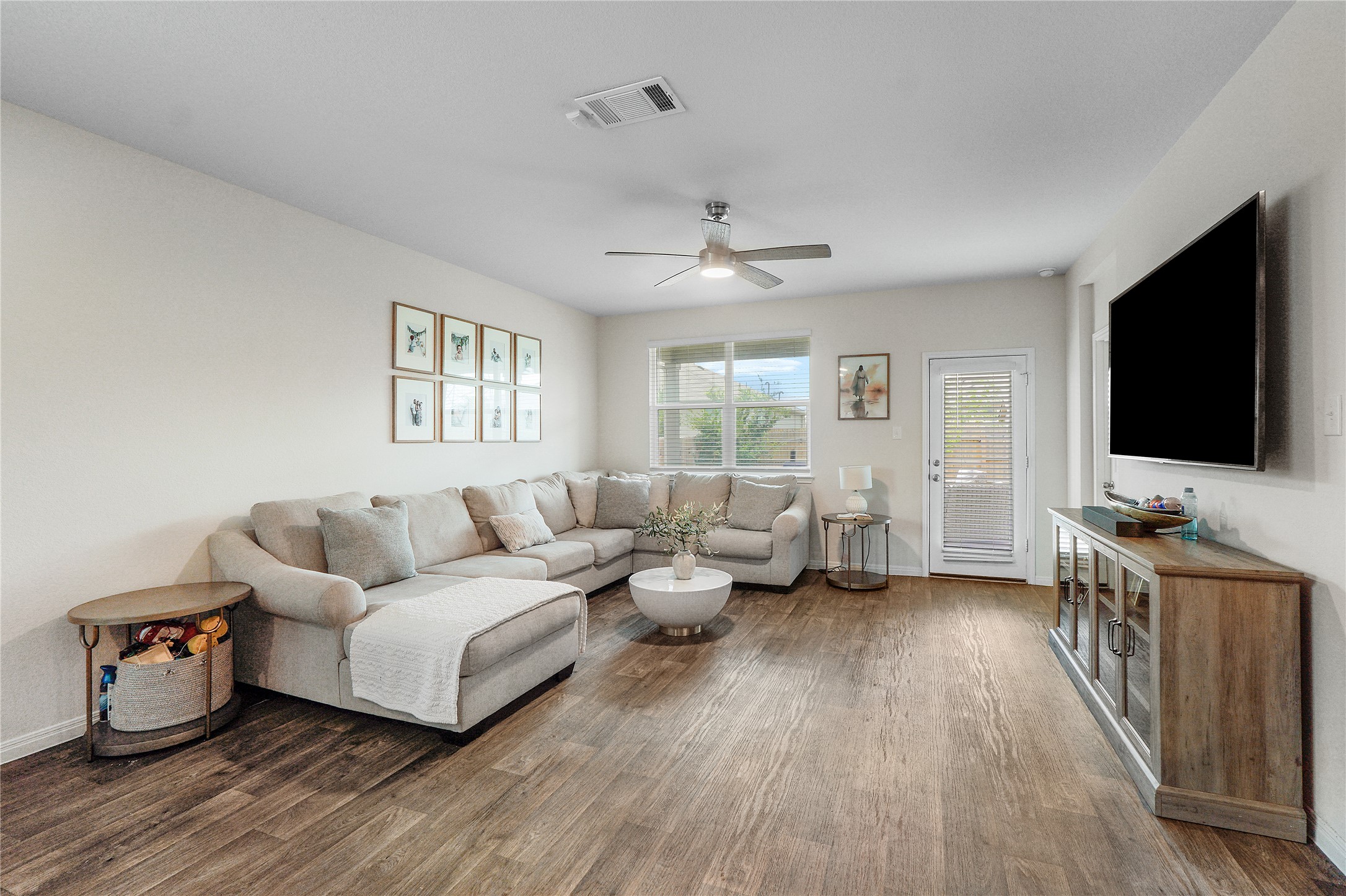 217 Evergreen Sumac Loop Kyle, TX 78640 - Photo 9 of 20 A naturally illuminated living room features durable hardwood flooring and a stylish ceiling fan.