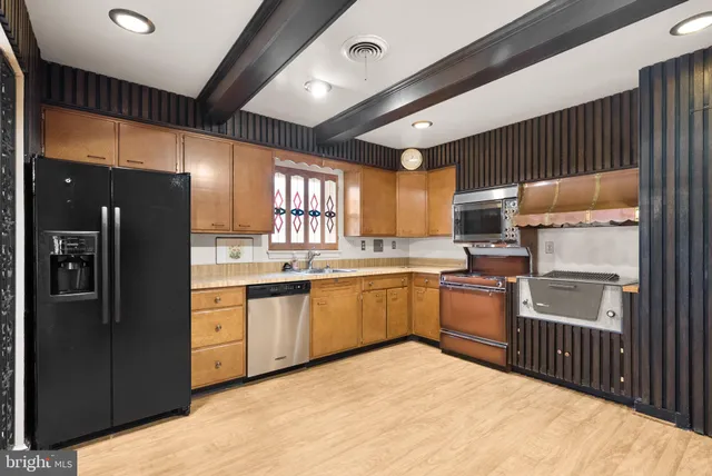 a kitchen with stainless steel appliances kitchen island granite countertop a refrigerator stove top oven and sink