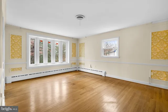 a view of an empty room with a window and wooden floor