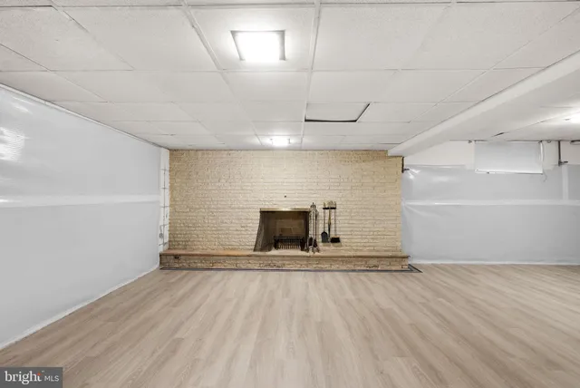 an empty room with wooden floor fireplace and windows