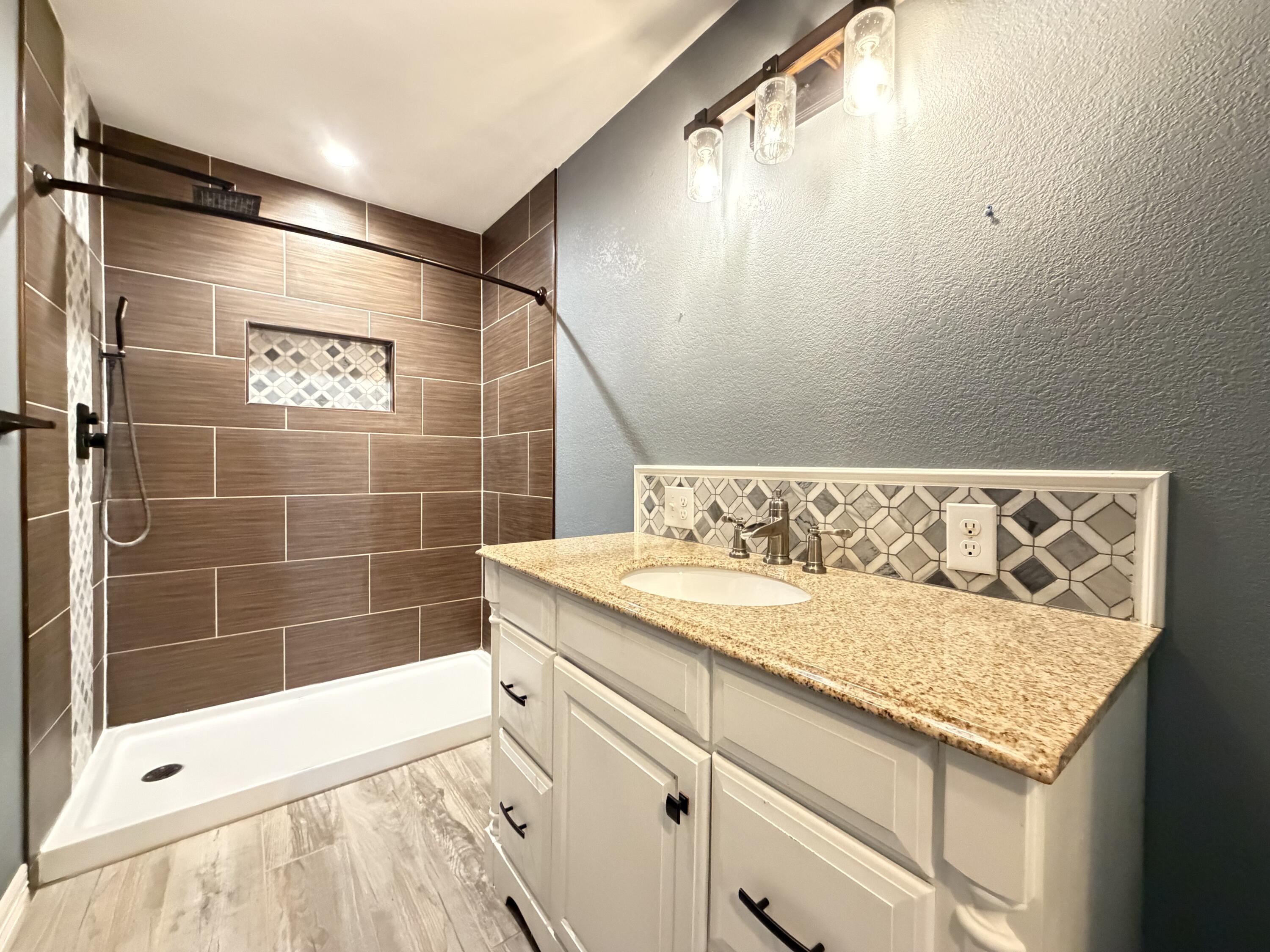 209 East 15th Street Littlefield, TX 79339 - Photo 11 of 18 a bathroom with a granite countertop sink and a shower
