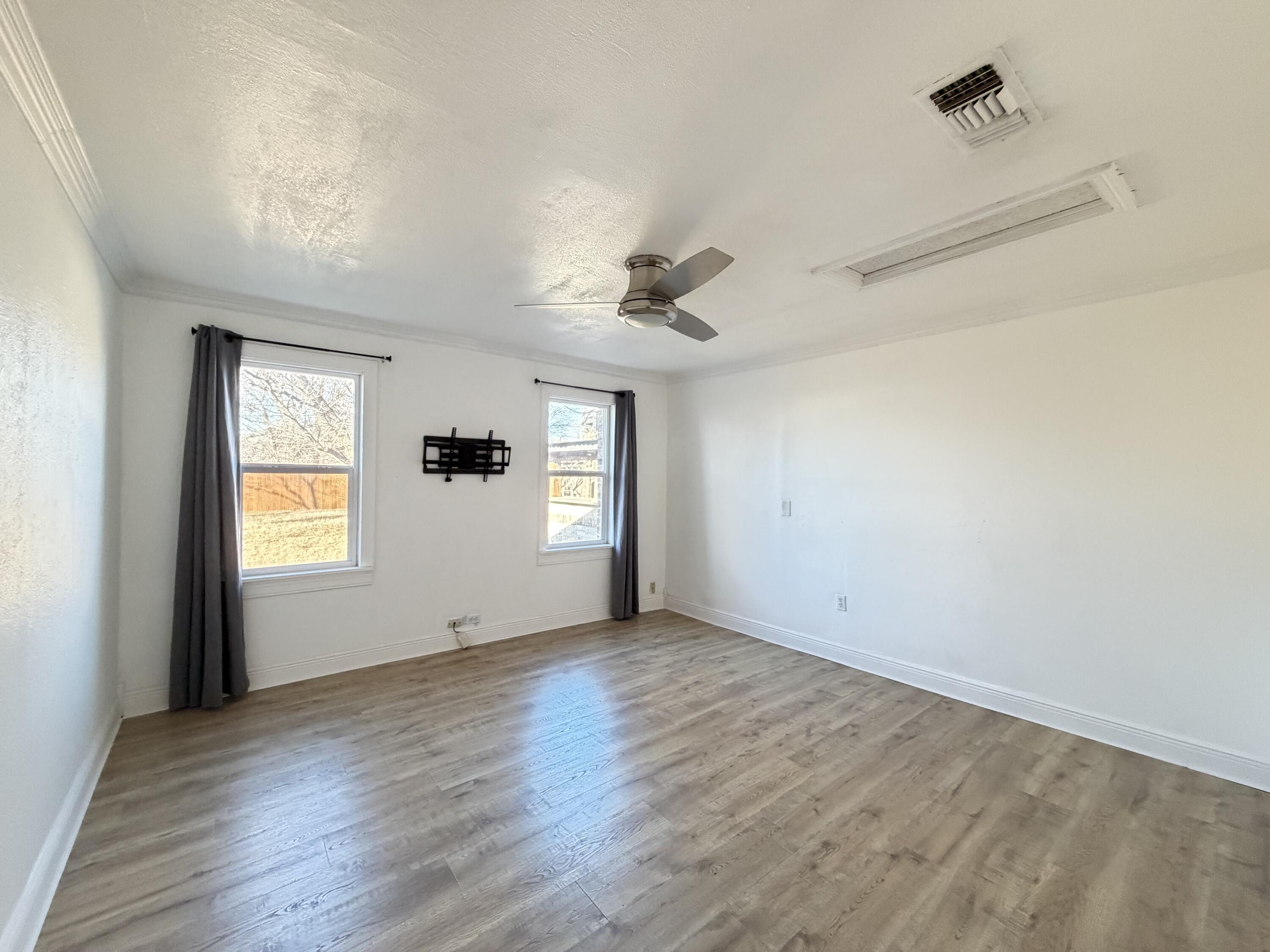 209 East 15th Street Littlefield, TX 79339 - Photo 13 of 18 an empty room with wooden floor and windows