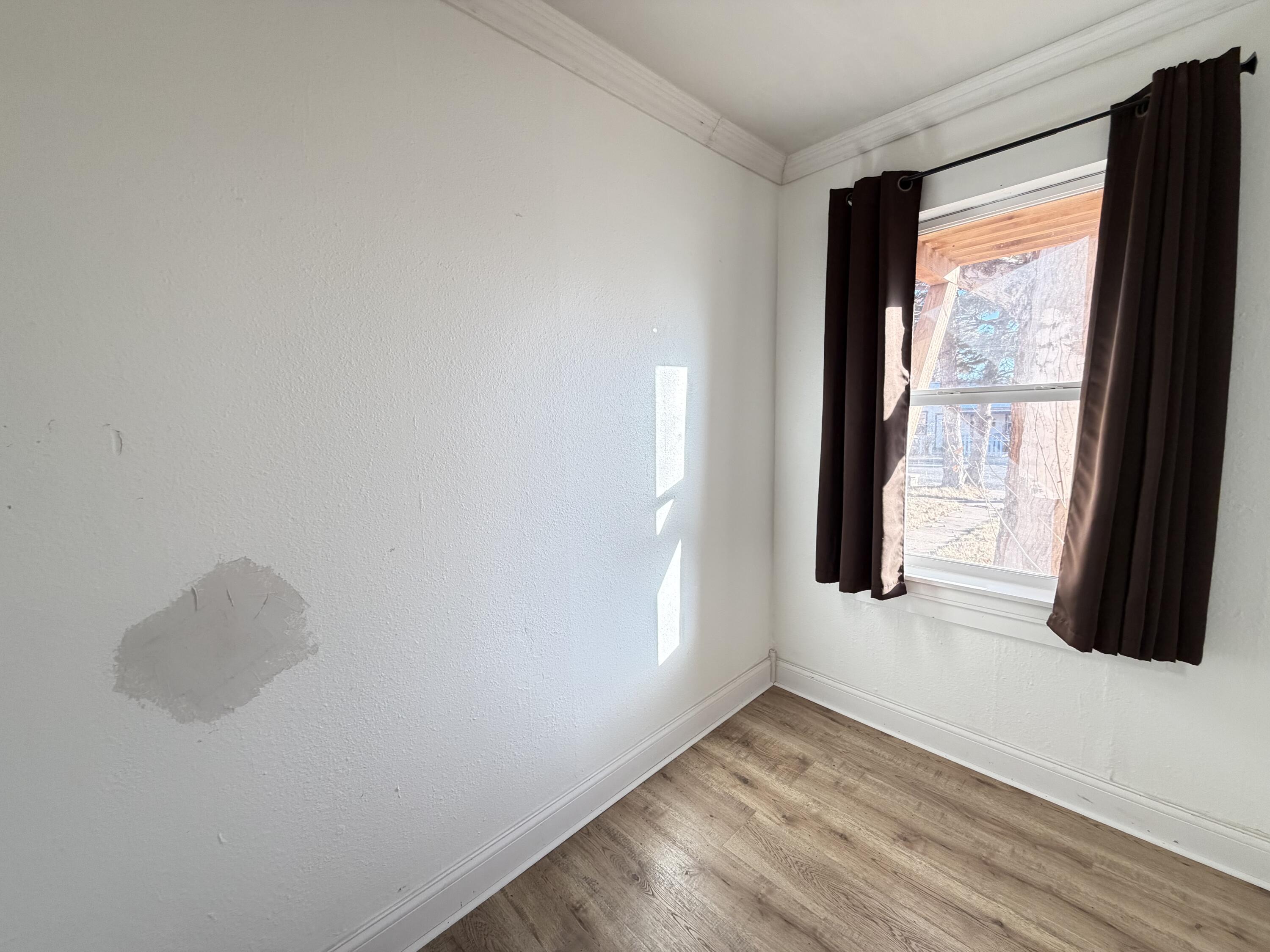209 East 15th Street Littlefield, TX 79339 - Photo 10 of 18 a view of an empty room with wooden floor and a window