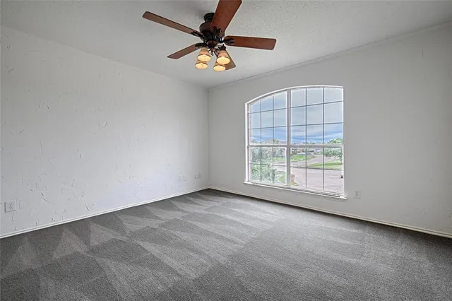 an empty room with windows and fan