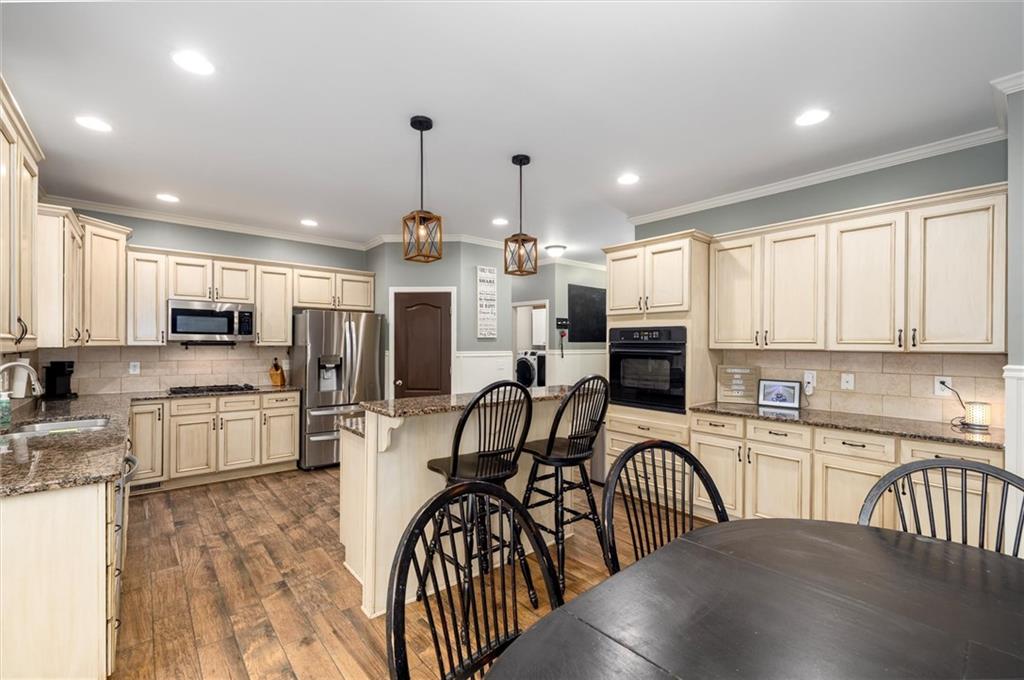 2016 Portage Point Southeast Lawrenceville, GA 30045 - Photo 7 of 43 a kitchen with stainless steel appliances granite countertop a refrigerator a stove top oven a sink dishwasher a dining table and chairs with wooden floor