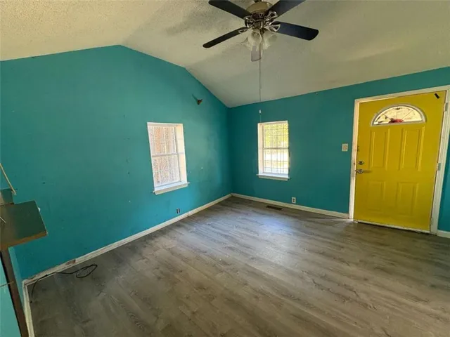 a view of empty room with window and wooden floor