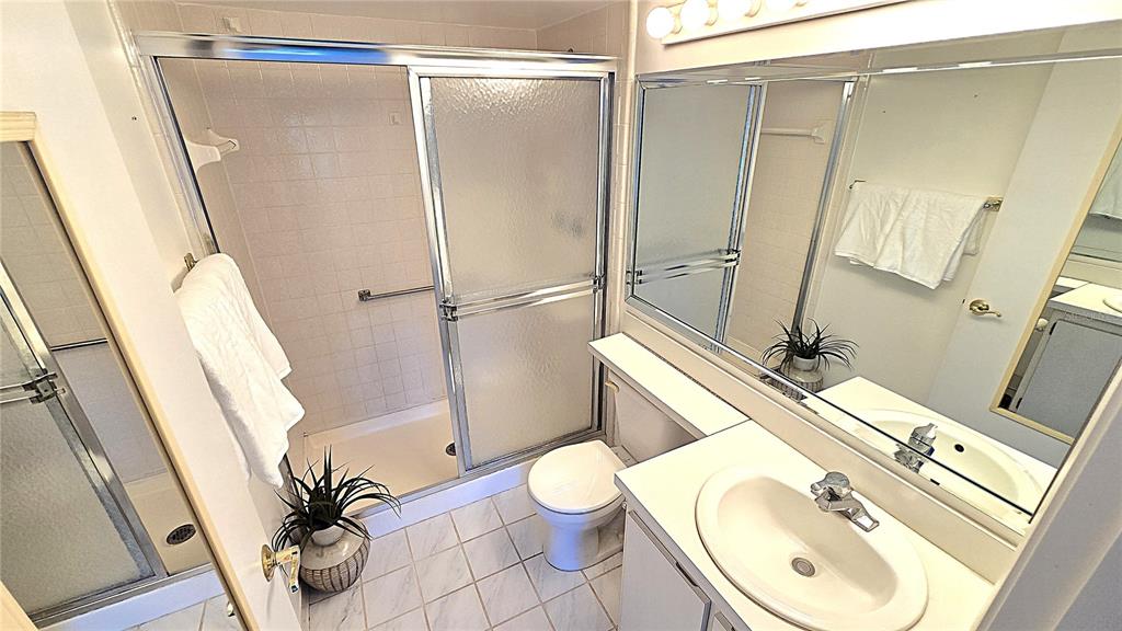 1109 Pine Ridge Circle West, Unit C1 Tarpon Springs, FL 34688 - Photo 28 of 50 a bathroom with a granite countertop sink toilet a mirror and shower