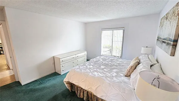 a bedroom with a bed and a flat tv screen on the dresser