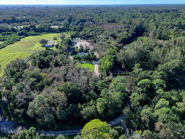 an aerial view of residential house with outdoor space and trees all around