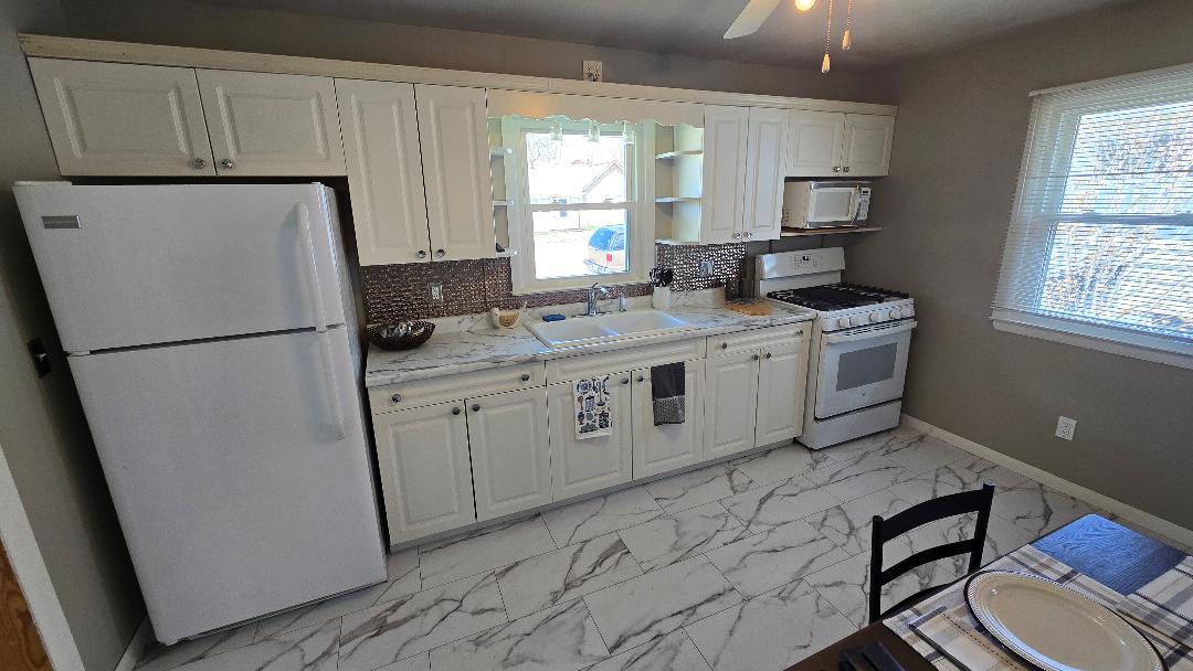 1124 13th Avenue Fulton, IL 61252 - Photo 11 of 27 a kitchen with a refrigerator a stove a sink and a window