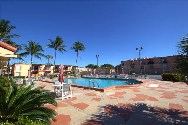 a view of a swimming pool with a lounge chair and palm trees