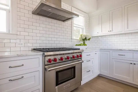 a kitchen with stainless steel appliances white cabinets and a stove top oven