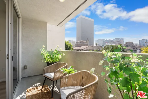 a roof deck with table and chairs and potted plants