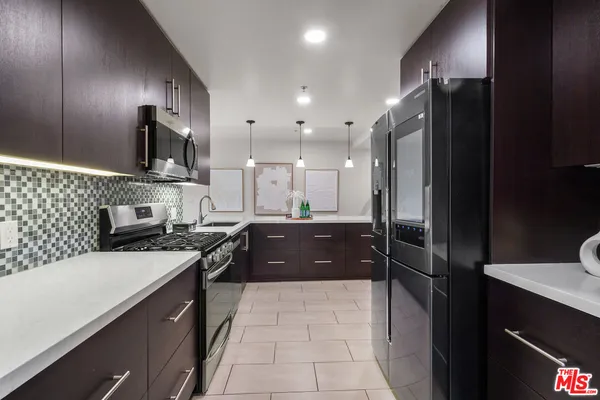 a large kitchen with stainless steel appliances granite countertop a refrigerator a sink and a stove