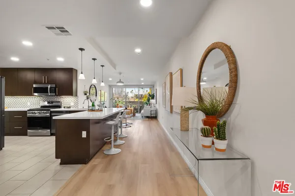 a living room with stainless steel appliances kitchen island a table chairs a sink a stove and a refrigerator