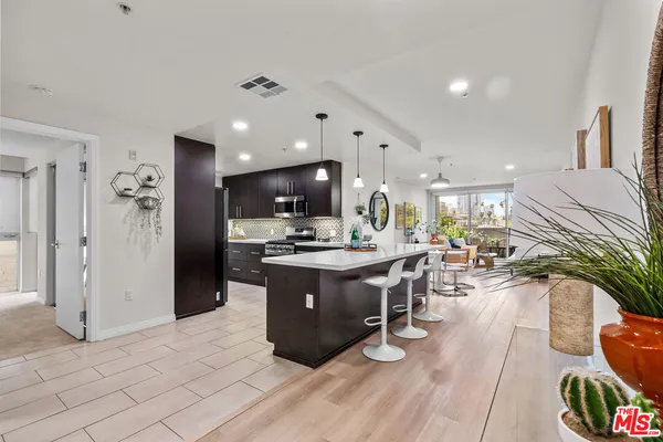a living room with stainless steel appliances kitchen island granite countertop furniture a rug kitchen view and a faucet