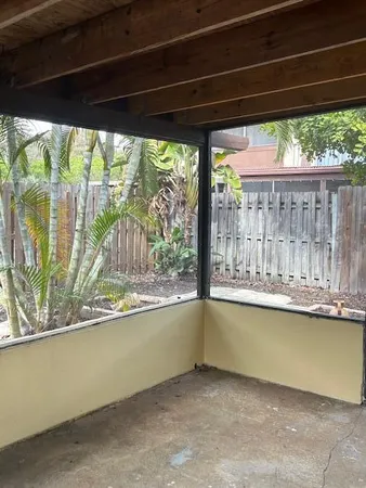 a view of a room with large windows and plants