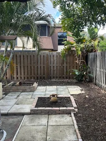 a view of a brick house with a small yard and large trees