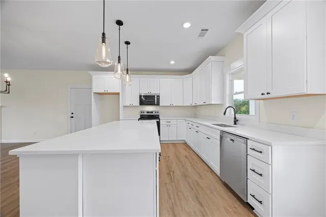 a kitchen with kitchen island sink stove and white cabinets with wooden floor