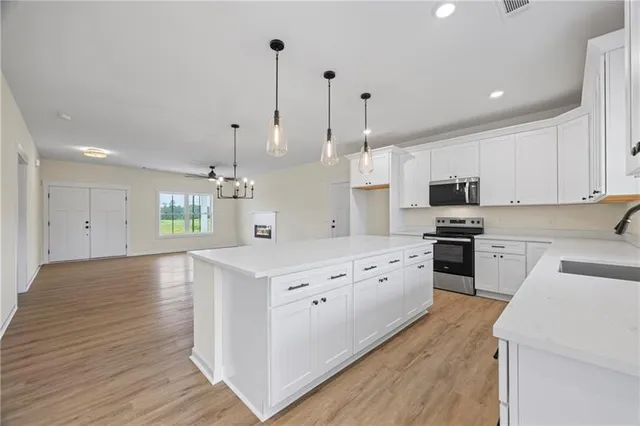 a large kitchen with granite countertop a white stove top oven and white cabinets