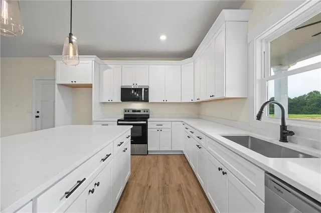 a kitchen with granite countertop white cabinets sink and stainless steel appliances