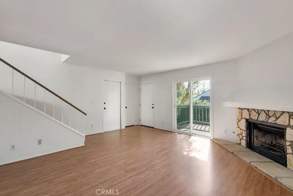 a view of an empty room with wooden floor fireplace and a window