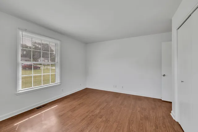 an empty room with wooden floor and windows