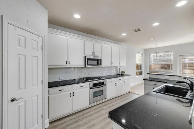 a kitchen with stainless steel appliances granite countertop a sink stove cabinets and microwave