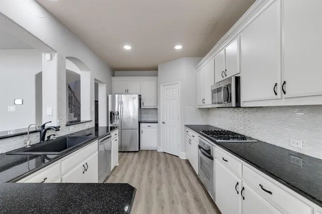 a large kitchen with granite countertop a large counter top stainless steel appliances and cabinets