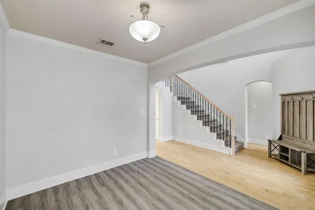 an empty room with wooden floor chandelier fan and windows