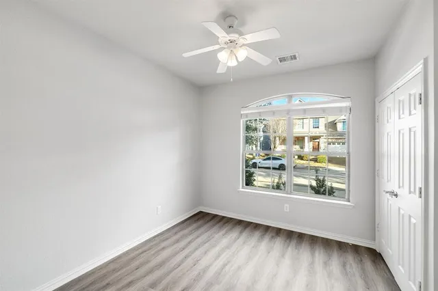 an empty room with wooden floor closet and windows