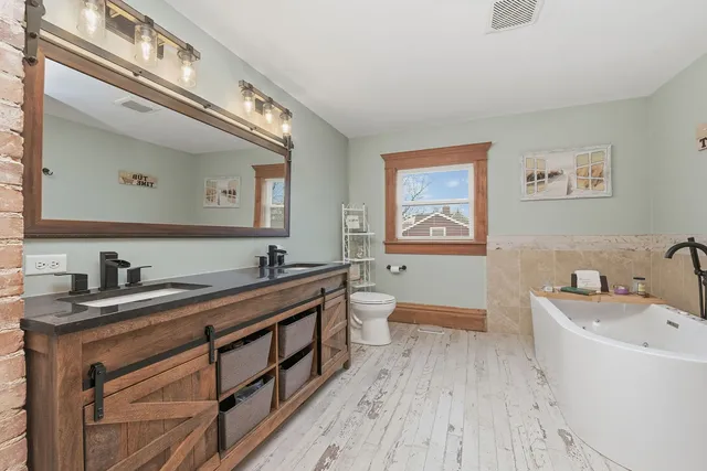 a spacious bathroom with a granite countertop sink a large mirror a toilet and bathtub