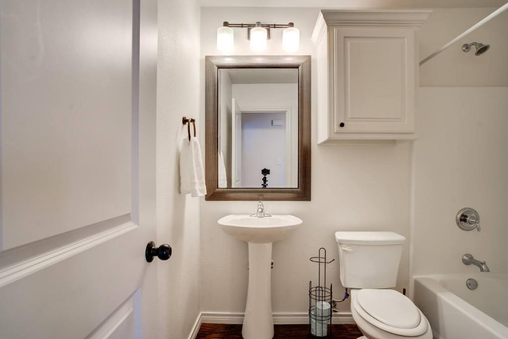 3107 33rd Street, Unit 1 Lubbock, TX 79410 - Photo 18 of 22 a bathroom with a toilet a sink and mirror
