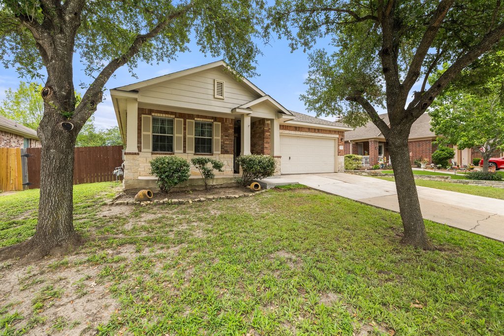 347 Spring Drive Kyle, TX 78640 - Photo 40 of 40 A welcoming front exterior offers a driveway, attached garage, and mature trees for natural shade.
