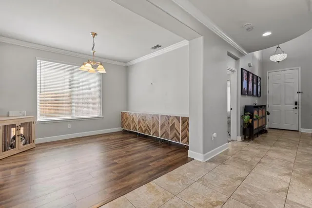 a view of an empty room with window and hardwood floor