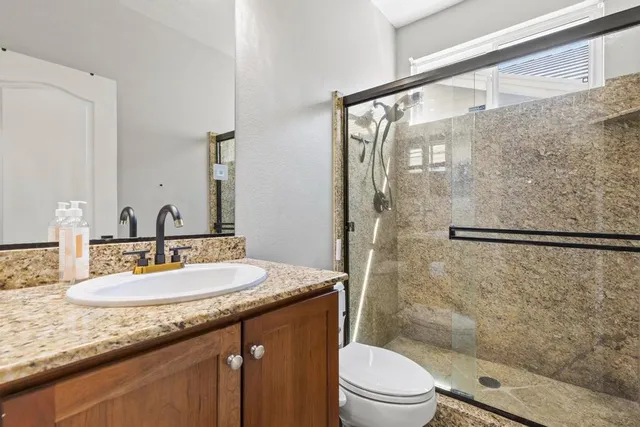 a bathroom with a granite countertop sink toilet and shower